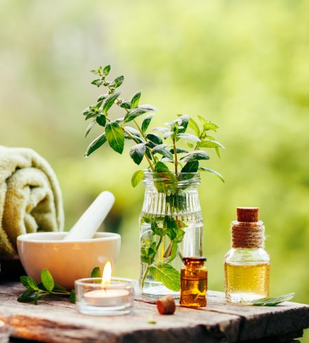 Spa background with essential oil, fresh peppermint and towel on wooden table outdoors. Selective focus.